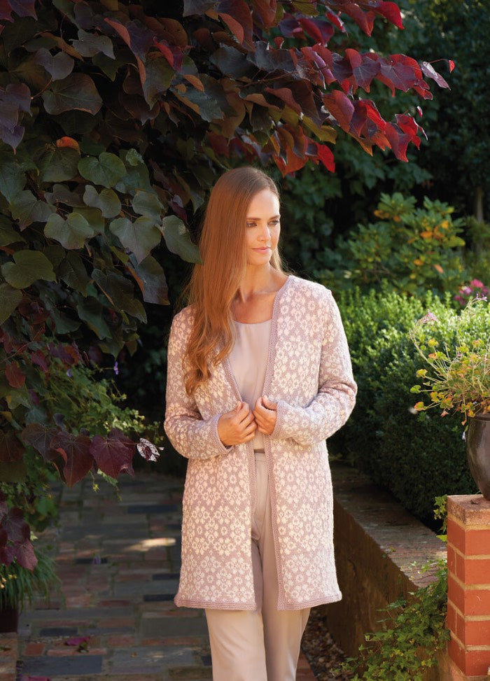 Model wearing hand-knitted garments from the Tea Garden collection by Martin Storey, including lace sweaters, striped tops, and floral wraps, styled in a botanical garden setting using Rowan yarns.