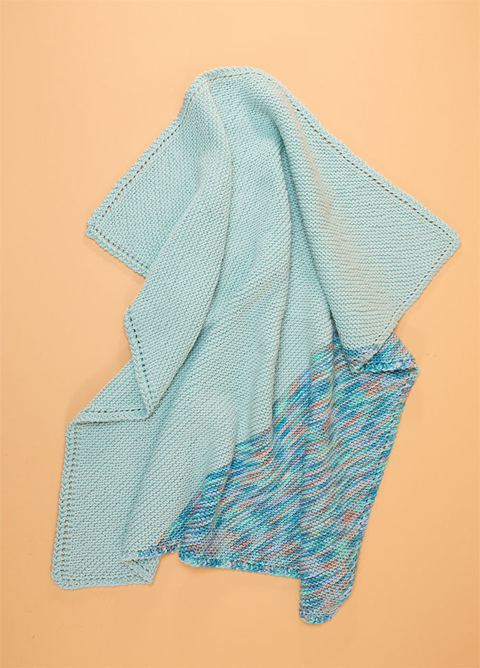 Light blue Florence Blanket with a lower section in pink, blue, and white pattern, finished with a textured knit border.