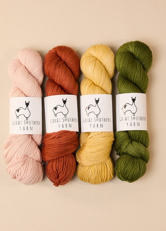 Four skeins of hand-dyed Australian merino yarn in various colors, ideal for DK weight projects.