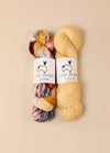 Two skeins of fingering weight yarn, labeled Great Southern Yarn Tawny Frog Owl, showcasing vibrant hand-dyed colors.