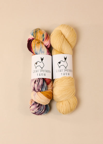 Two skeins of fingering weight yarn, labeled Great Southern Yarn Tawny Frog Owl, showcasing vibrant hand-dyed colors.