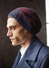 A side profile of a man in a dark coat and beanie, looking pensive. Soft lighting highlights the textured knit, creating a contemplative mood.