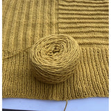 Ball of yellow yarn on a knitted fabric background