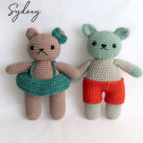 Two crocheted teddy bears from the Intro to Amigurumi class. The left bear wears a teal skirt, and the right bear wears red shorts. The word "Sydney" is in the top left corner.