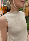 Close-up of the Ivy Top in ivory ribbed knit with high neckline and sleeveless design, worn outdoors with greenery in the background.