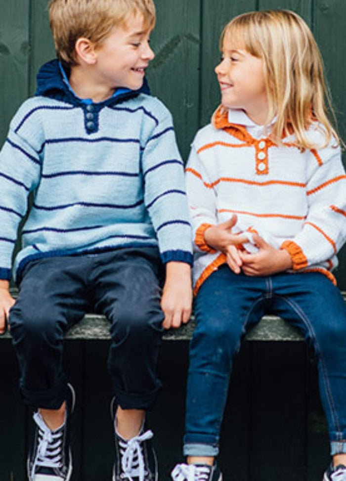 Jamie Sweater: Two children sitting on a bench wearing striped sweaters with buttoned collars‚Äîone in light blue and dark blue, the other in white and orange.