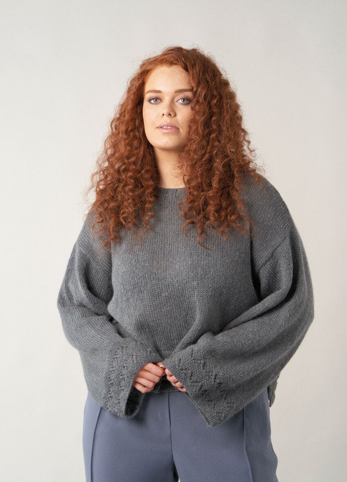 Loose-fitting cardigan in deep forest green with a straight silhouette, finished with ribbed edging and worn open over a shirt.