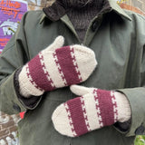 A woman showcases striped mittens, designed from the wrist up, utilizing the Magic Loop method or double-pointed needles.