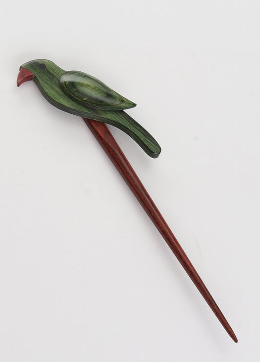  A green and red bird resting on a wooden stick, highlighting the charm of colorful beech wood accessories for knitters.