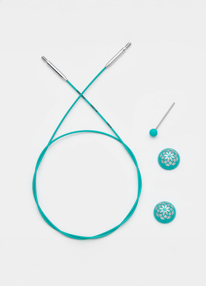 A pair of turquoise knitting cable next to a button, showcasing vibrant color and elegant design for stylish accessories.