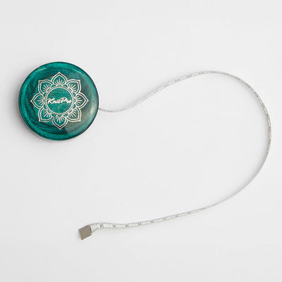  Teal wooden tape measure with a green button, white cord, and gold lotus design, part of the Mindful Collection accessories.