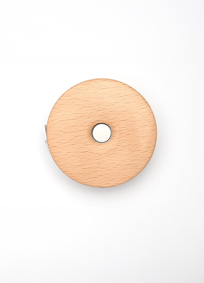 Teal wooden tape measure with a lotus design, featuring a central hole for smooth retraction of the 152cm/60” tape.