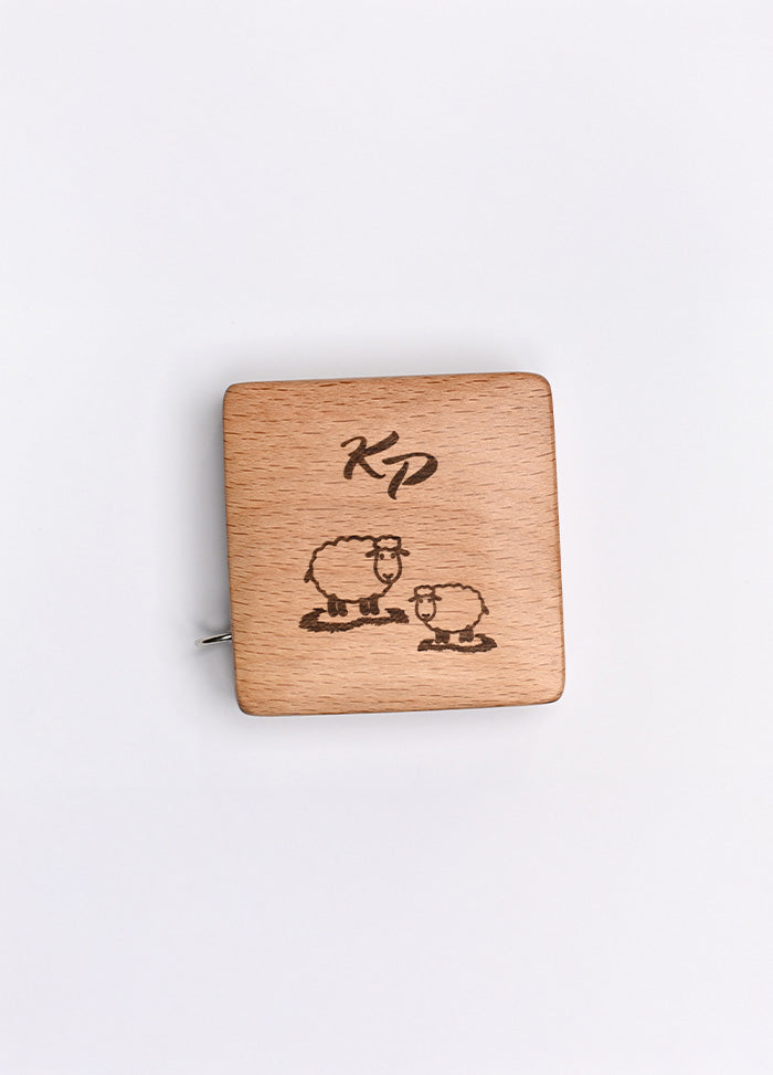 A beechwood box with a sheep motif and KP logo, housing a 150cm tape measure with metric and imperial markings.
