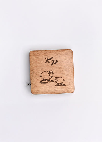 A beechwood box with a sheep motif and KP logo, housing a 150cm tape measure with metric and imperial markings.