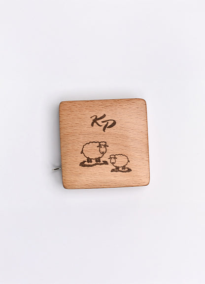 A beechwood box with a sheep motif and KP logo, housing a 150cm tape measure with metric and imperial markings.
