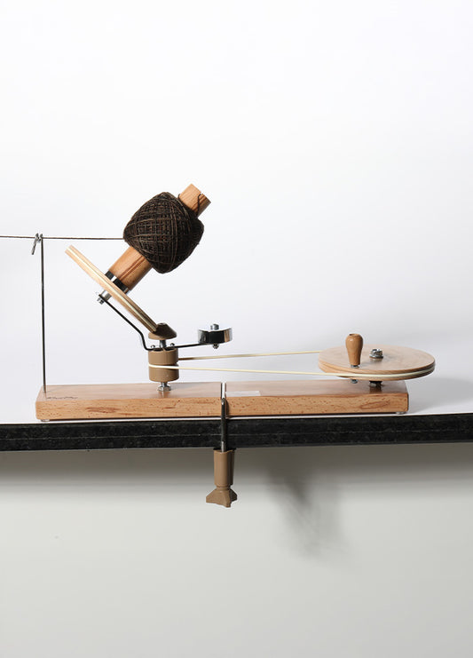 A handcrafted spinning wheel with a wooden handle and spindle, designed for smooth yarn winding and stability on surfaces.