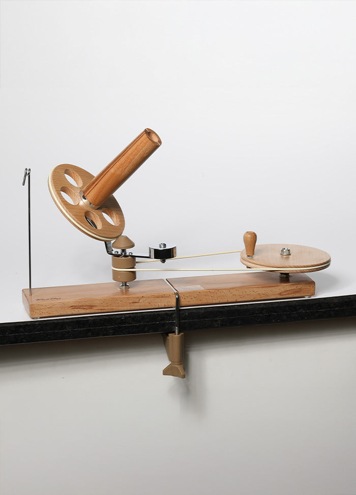 Elegant spinning wheel on a wooden stand, made of laminated birch, designed for effortless yarn winding and stability.