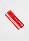 A red ruler against a white background, designed to measure knitting needle sizes and gauge with a clear magnifying feature.