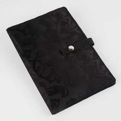 Black knitting case with a floral pattern, designed to securely hold and display crafting patterns and charts for easy access.