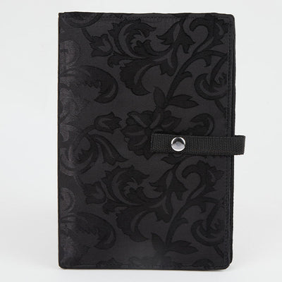 Black knitting bag with a floral pattern, designed to hold and display crafting patterns securely while working on projects.