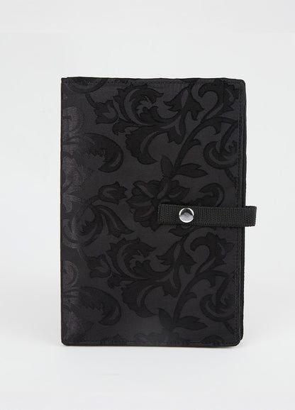 Black knitting bag with a floral pattern, designed to hold and display crafting patterns securely while working on projects.