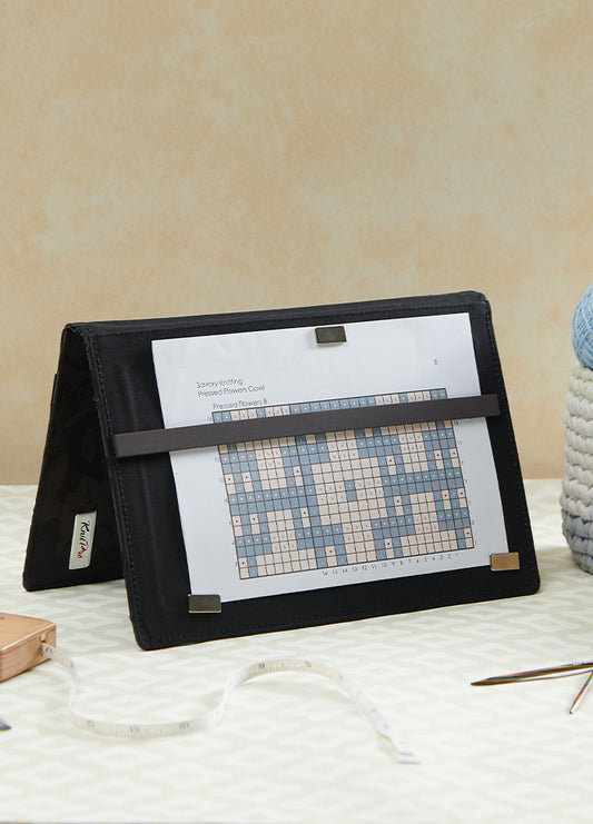  A crafting table features a magma chart keeper, a cross stitch kit, and a book, highlighting essential tools for crafters.