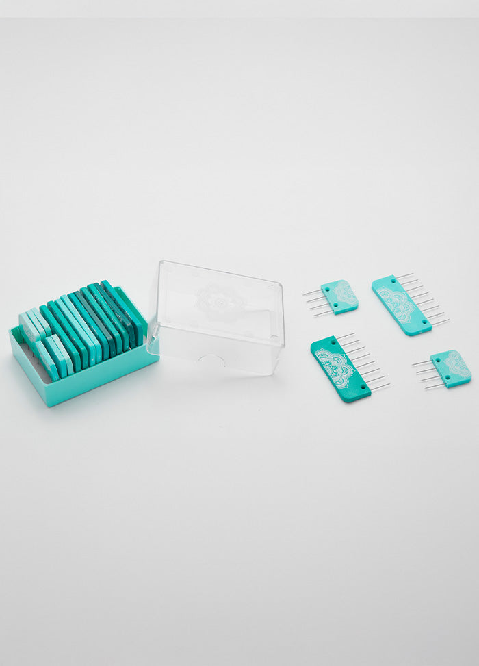 A set of teal knit blockers , some in a clear plastic case and four placed separately on a white surface.