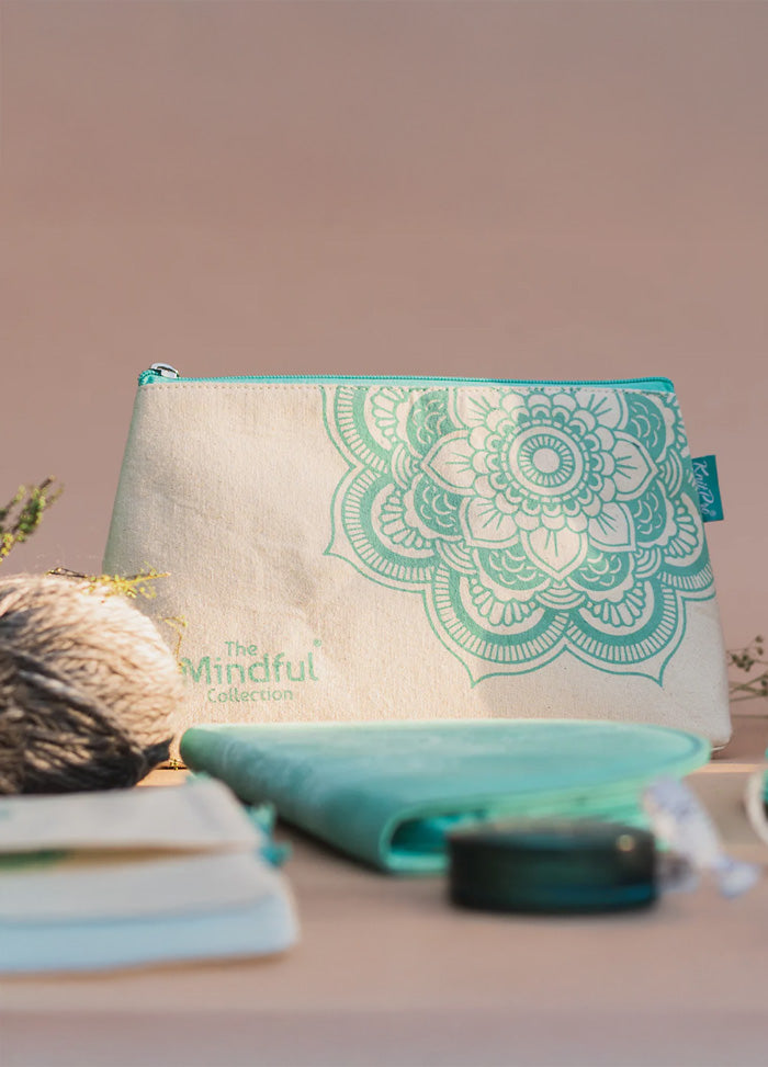 Green and white purse with a floral design, featuring a mandala charm and zippered pocket for knitting supplies.