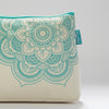 Floral-patterned white and turquoise cosmetic bag, ideal for knitting supplies, with a mandala charm and inner pocket.