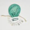 A green bag with a silver coin purse and silver chakra charm set, showcasing fine craftsmanship and a multipurpose pouch.