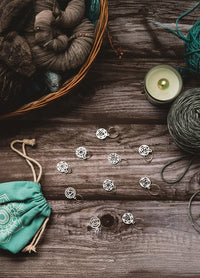 A basket filled with colorful yarn, a lit candle, and a bag of yarn, showcasing a cosy crafting atmosphere.