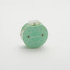 Row counter with a flower design in green and white, used for tracking rows on a teal knitting tool in a cotton pouch