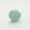 Small green row counter with a flower design, part of a teal knitting tool for tracking rows, in a drawstring cotton case.