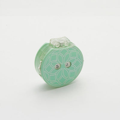 Small green row counter with a flower design, part of a teal knitting tool for tracking rows, in a drawstring cotton case.