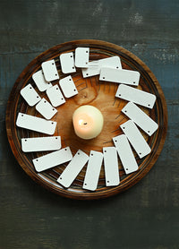 A wooden plate features a candle and knit blockers, creating a warm setting ideal for knitting or crochet projects and relaxation.