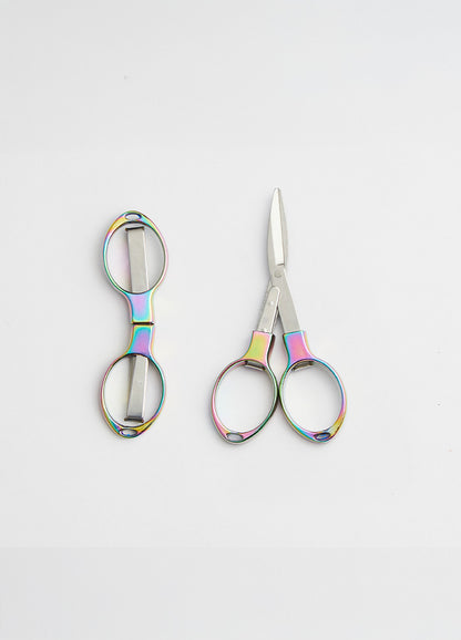 Colourful scissors with a rainbow handle and shiny metal blades, designed to fold for protection from sharp points.