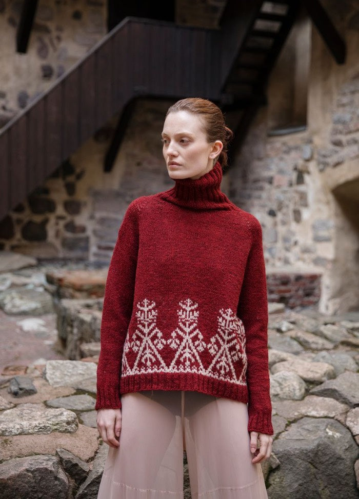 Sampo: red sweater with white geometric hem pattern, photographed outdoors near a stone wall and wooden stairs.