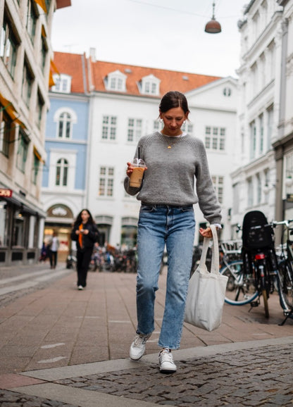 Coffee Run Sweater: Casual grey knit styled with jeans and sneakers, captured mid-walk with iced coffee and tote.