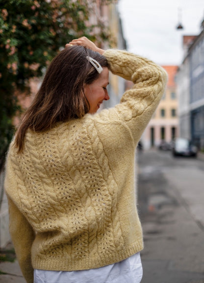 Limoncello Cardigan: Sunny yellow knit with cable and lace details, worn on a city street with greenery.