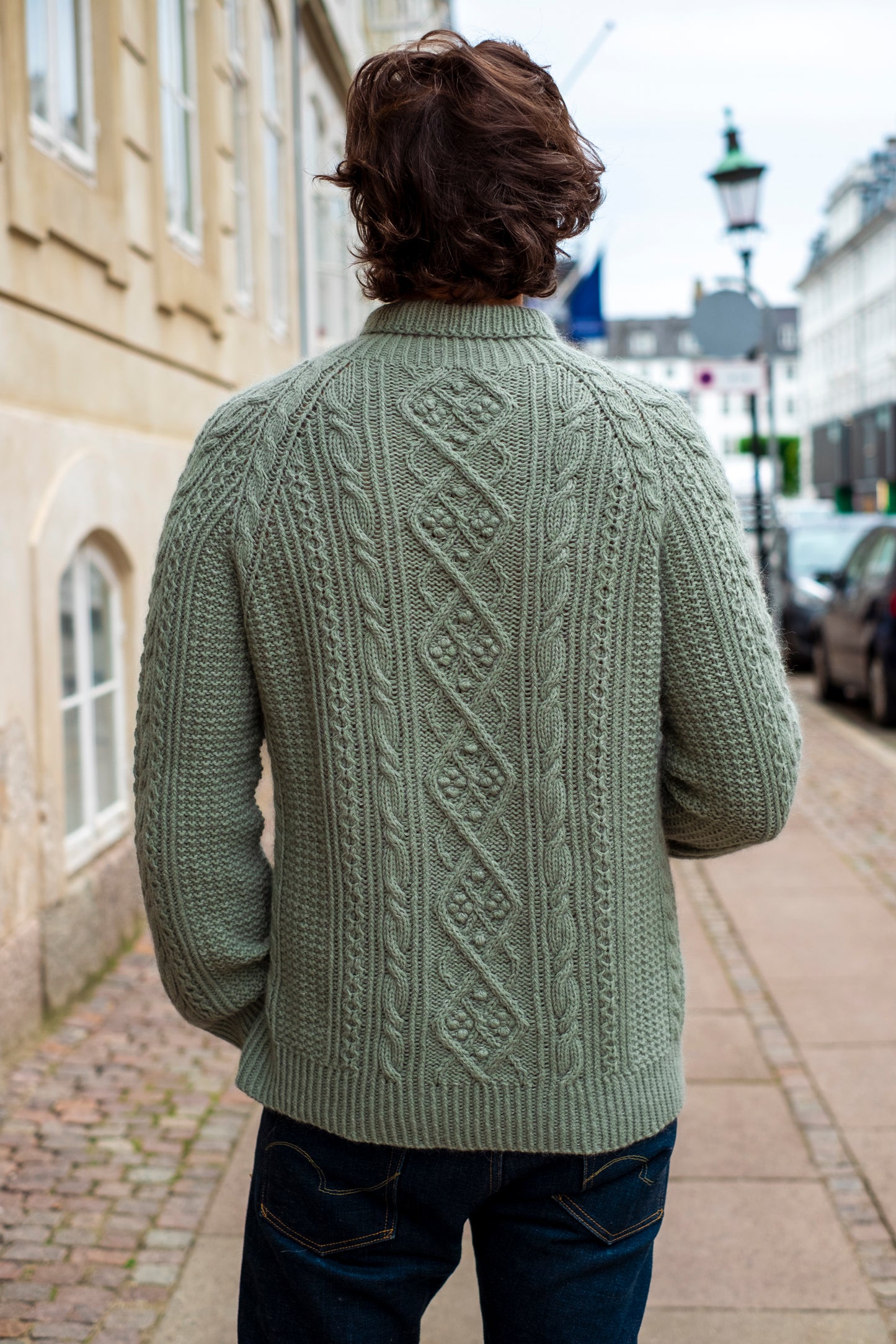 My Favourite Story Sweater:Green cable-knit design with rich texture, worn in an urban street setting.