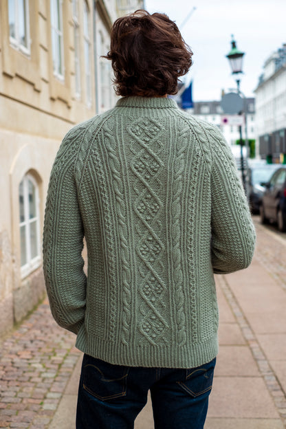 My Favourite Story Sweater:Green cable-knit design with rich texture, worn in an urban street setting.