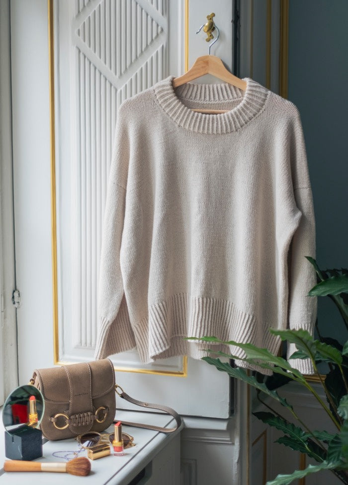 Simple Things Sweater:Neutral-toned knit displayed on a hanger with accessories and greenery in a styled interior.