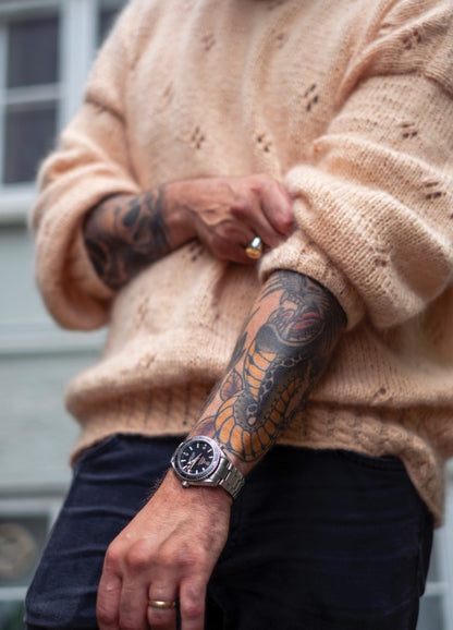 Take Me Out Sweater: Light beige knit with eyelet details, styled with rolled sleeves and visible tattoos.