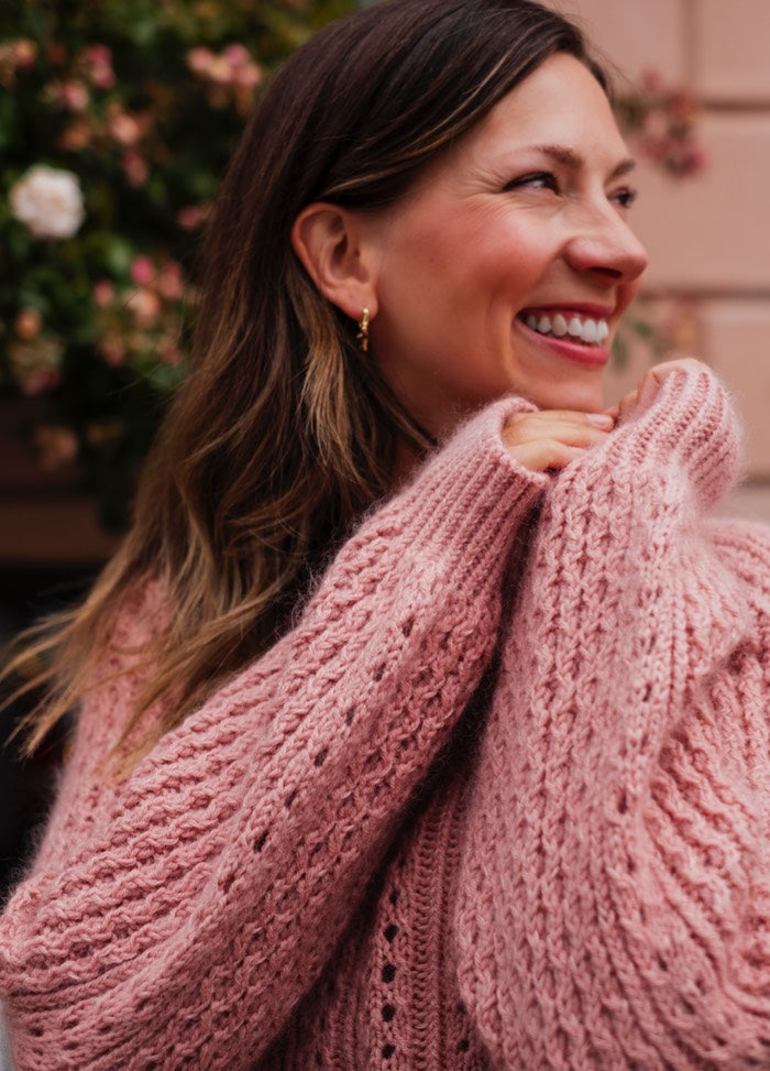 Urban Romance Sweater: Soft pink knit with delicate lace detailing, styled outdoors among greenery.