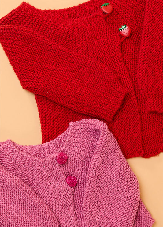 Two hand-knitted baby cardigans – red cardigan with strawberry-shaped buttons and pink cardigan with rose-shaped buttons, showcasing charming details for handmade babywear.