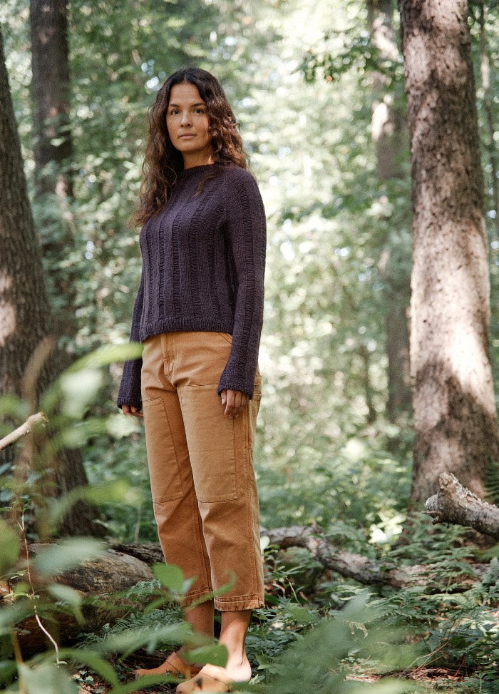 Bambuzal Sweater: dark purple knit sweater worn with light brown pants, in a forested outdoor setting.