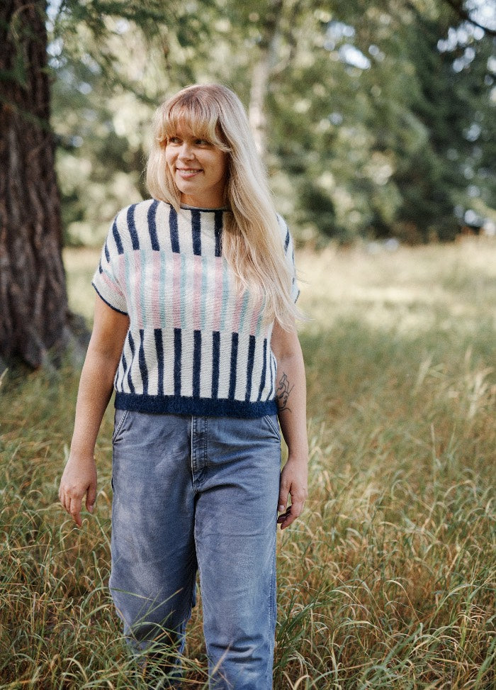 Dagdrom Top: striped short-sleeved knit top in dark and light tones, worn with high-waisted jeans in a grassy outdoor setting.
