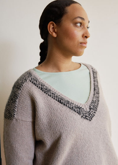 Light grey V-neck sweater with dark grey and black pattern at neckline and shoulders, layered over a light green shirt.