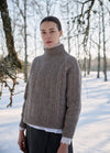 Ribbed turtleneck sweater worn outdoors in a snowy landscape with leafless trees.