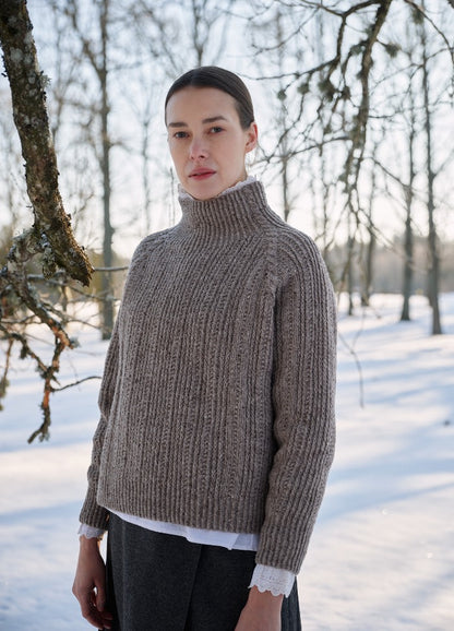 Ribbed turtleneck sweater worn outdoors in a snowy landscape with leafless trees.